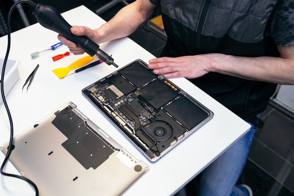 Technician Using Heat Gun for Laptop Repair in Service Center